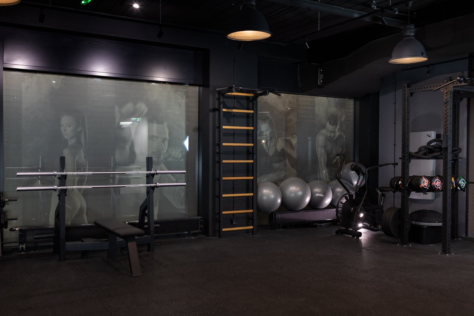 Sala fitness — drabinki gimnastyczne, stojak z obciążeniem, sala fight za przeszkloną ścianą